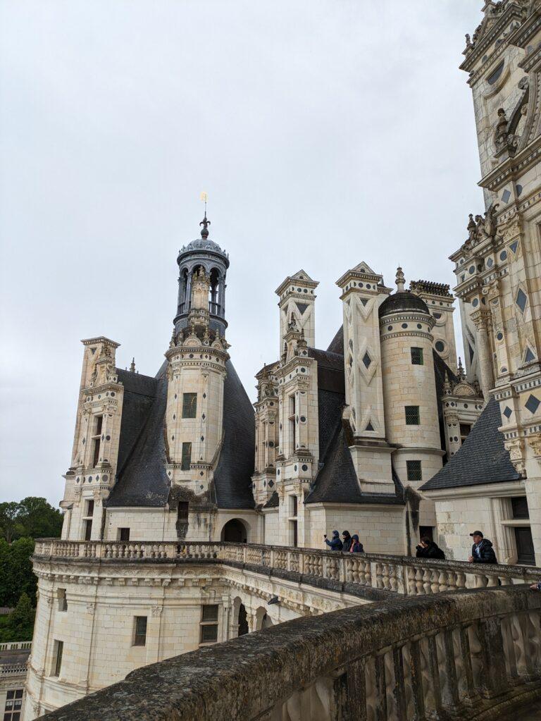 A Day at Château de Chambord: The Crown Jewel of the Loire Valley, Château de Chambord aerial view Loire Valley largest castle, Chambord Castle double helix staircase designed by Leonardo da Vinci, Château de Chambord façade with Renaissance and medieval architecture, Chambord Castle rooftop terraces with chimneys and spires, Château de Chambord grand entrance courtyard with visitors, Interior of Chambord Castle ornate ceiling and stone carvings, Château de Chambord reflected in moat at sunrise, Chambord Castle hunting lodge history exhibition room, Château de Chambord gardens and surrounding forest, Night view of Chambord Castle illuminated against dark sky