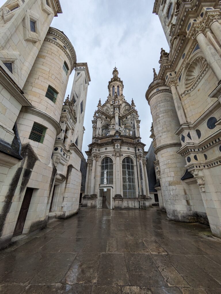 A Day at Château de Chambord: The Crown Jewel of the Loire Valley, Château de Chambord aerial view Loire Valley largest castle, Chambord Castle double helix staircase designed by Leonardo da Vinci, Château de Chambord façade with Renaissance and medieval architecture, Chambord Castle rooftop terraces with chimneys and spires, Château de Chambord grand entrance courtyard with visitors, Interior of Chambord Castle ornate ceiling and stone carvings, Château de Chambord reflected in moat at sunrise, Chambord Castle hunting lodge history exhibition room, Château de Chambord gardens and surrounding forest, Night view of Chambord Castle illuminated against dark sky