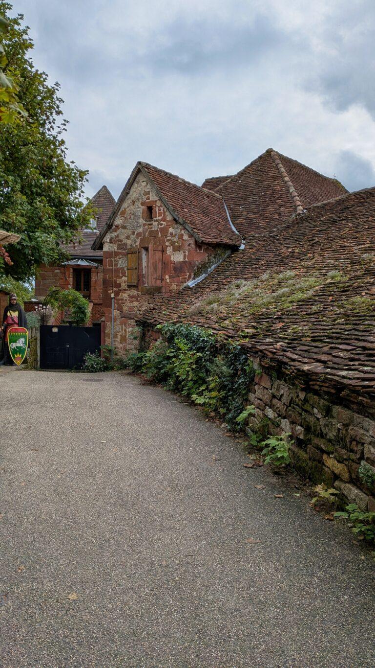 Collonges-la-Rouge alley, red stone walls, flowered balconies, charming street, Collonges-la-Rouge: The Red Stone Gem of France, Collonges-la-Rouge village, red sandstone houses, medieval architecture, Limousin France, Collonges-la-Rouge alley, red stone walls, flowered balconies, charming street, saru's postcards, beautiful villages of France