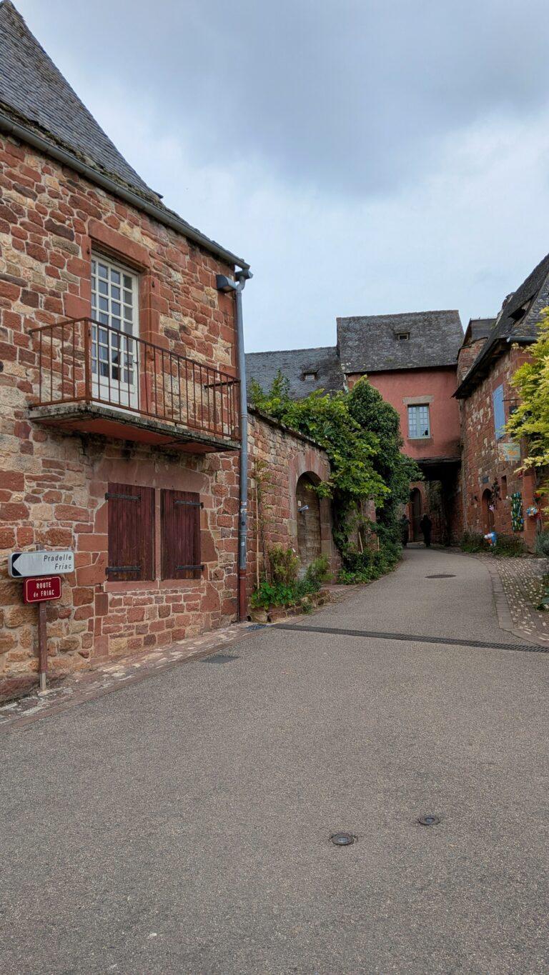 Collonges-la-Rouge alley, red stone walls, flowered balconies, charming street, Collonges-la-Rouge: The Red Stone Gem of France, Collonges-la-Rouge village, red sandstone houses, medieval architecture, Limousin France, Collonges-la-Rouge alley, red stone walls, flowered balconies, charming street, saru's postcards, beautiful villages of France