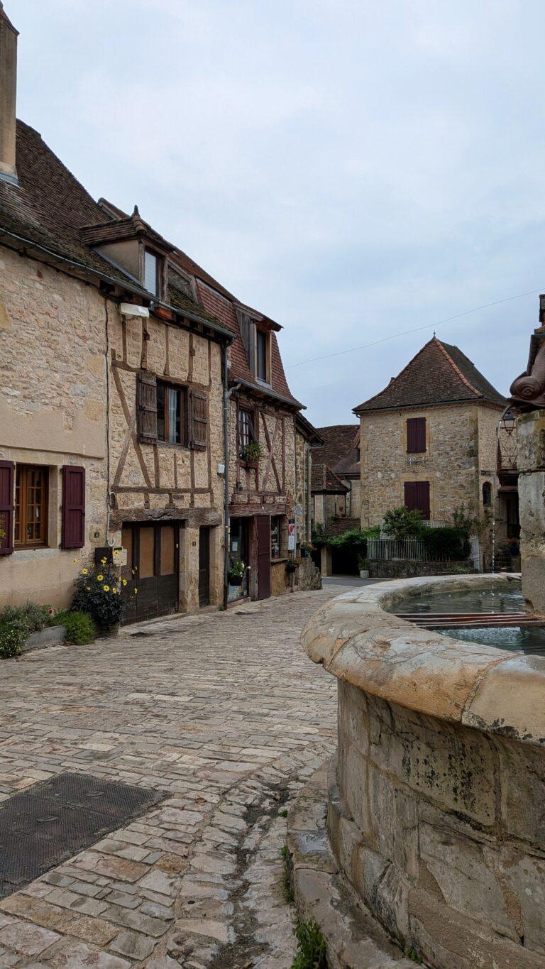 autoire village, golden stone houses, medieval architecture, lot region, france autoire valley, limestone cliffs, picturesque landscape, south west france autoire rooftops, panoramic view, charming french village, countryside scenery, saru's postcards, French village
