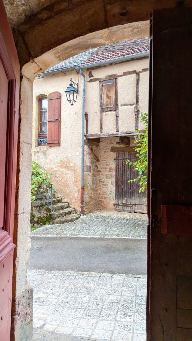 Loubressac: The Hilltop Jewel of the Lot Valley, saru's postcards, church of saint jean baptiste loubressac, romanesque church, historic building, village center, france chateau de loubressac, stone castle, hilltop fortress, panoramic view, French heritage, loubressac viewpoint, valley view, dordogne valley, scenic landscape, lot region lot valley from loubressac, rolling hills, green fields, beautiful france, countryside view, loubressac houses, flowered balconies, limestone walls, charming details, travel destination old wooden door loubressac, rustic french house, village charm, historical architecture, loubressac sunset, golden light, picturesque rooftops, lot countryside, magical moment morning in loubressac, sunlight on stone houses, peaceful atmosphere, hidden gem france village lane loubressac, flowers and ivy, romantic walk, travel photography, postcard moment